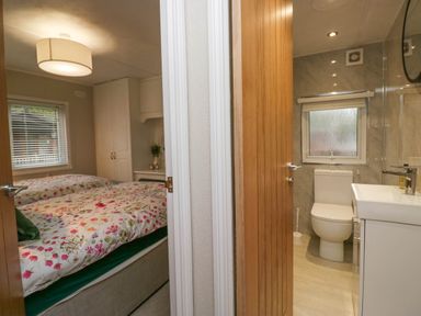 A bedroom with two beds next to a bathroom with a toilet and sink at Robins Lodge White Cross Bay near Troutbeck Bridge