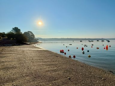 A beach with water and buoys in the bay at The Studio in Feock near Truro