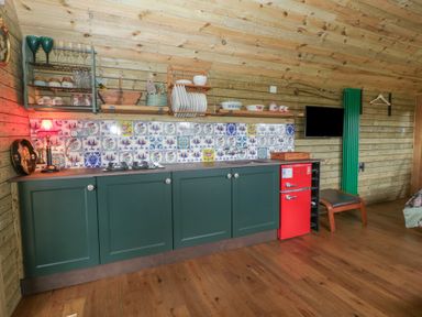 A kitchen with cabinets and a red refrigerator at Shepherd Hut’s in Bristol