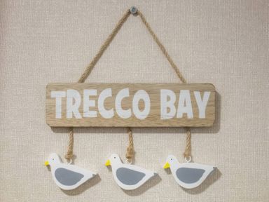 A wooden sign reading Trecco Bay with three seagull decorations at Pines 15 Porthcawl