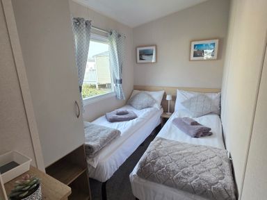 A bedroom with twin beds and a wardrobe at Pines 15 in Porthcawl