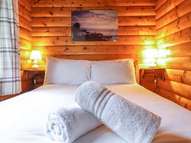 A bedroom with a bed and towels at Y Bwthyn Pren, Cabin 209, Trawsfynydd