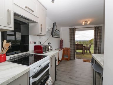 A kitchen area with stove toaster kettle and utensils with a view of outdoor seating at Twilight in Raglan