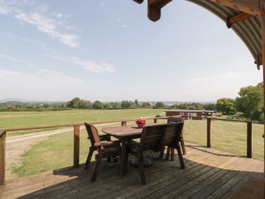 An outdoor seating area with a table and chairs overlooking fields at Twilight in Raglan