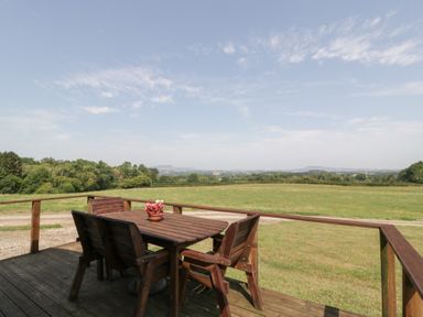 An outdoor seating area with a wooden table and chairs at Twilight in Raglan