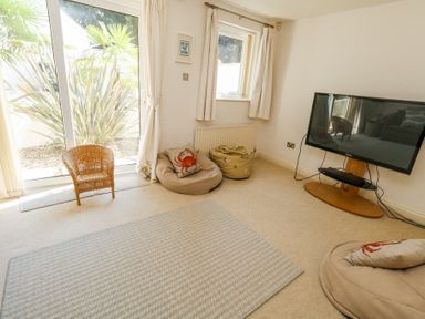 A living room with bean bags a television and a small wicker chair at 6 Red Sails in Sandbanks