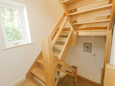 A wooden staircase with a window and framed picture on the wall at 6 Red Sails in Sandbanks