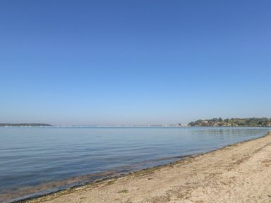 A sandy beach with calm water and clear sky at 6 Red Sails in Sandbanks