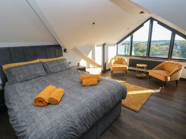 A bedroom with a bed and chairs at 10 Brython Place in Tenby