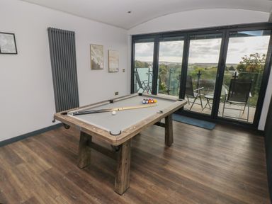 A game room with a pool table and large windows at 10 Brython Place Tackley