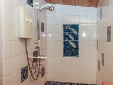 A shower area with wall tiles and an electric shower unit at The Boat House in Ashprington