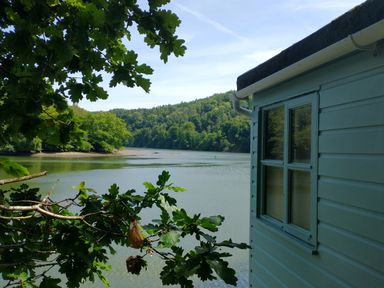 A view of water and trees from the side of a building at The Sharpham Boat House in Ashprington