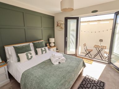 A bedroom with a bed and open doors leading to an outside area at Craster House in Seahouses
