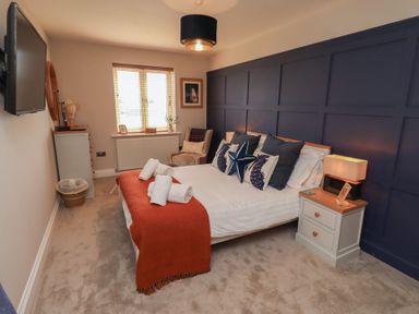 A bedroom with a bed, bedside table, and television at Craster House in Seahouses
