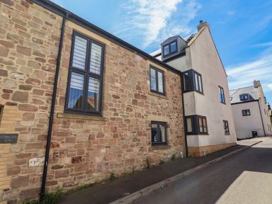 An exterior view of a stone building with windows at Craster House Seahouses