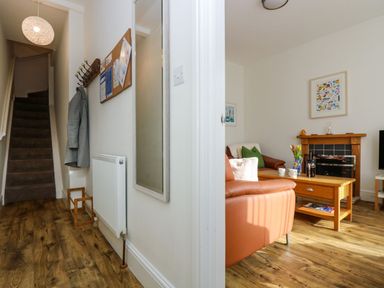 An entryway with stairs and coat hooks leading to a living room with a fireplace and leather sofas at Breakers Point in St Ives