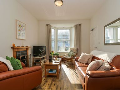 A living room with leather sofas a wooden coffee table a television a fireplace and a window with vertical blinds at Breakers Point in St Ives