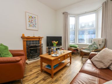 A living room with brown leather sofas a wooden coffee table and a fireplace at Breakers Point in St Ives