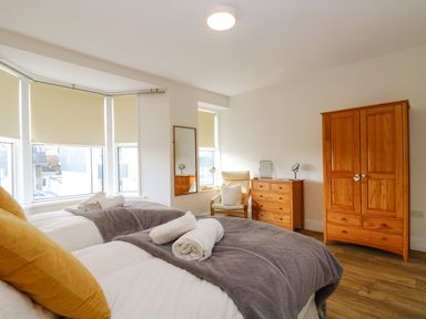 A bedroom with two single beds wooden wardrobe and chest of drawers at Breakers Point in St Ives
