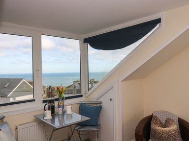 A small corner area with a table set for coffee near windows showing an ocean view at Breakers Point in St Ives