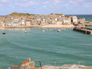 A coastal town with boats in the water and buildings along the shore at Breakers Point in St Ives