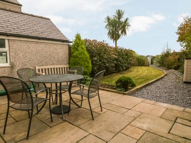 A garden with a table and chairs at Rhianfa in Newborough