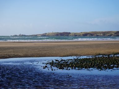 A beach view with waves and an island in the distance at Rhianfa Newborough