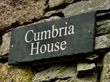 A sign for Cumbria House on a stone wall at Cumbria house