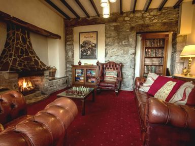 A living room with a fireplace and chess set at Noddfa Country House Harlech