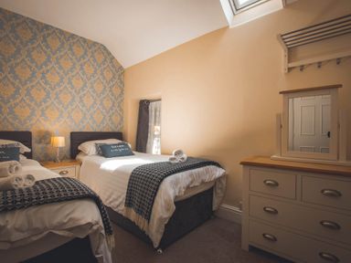 A bedroom with two beds and a dressing table at Noddfa Country House in Harlech