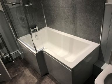 A bathroom with a bathtub and a shower screen at Noddfa Country House in Harlech