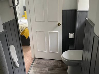 A bathroom with a toilet and door leading to a bedroom at Noddfa Country House Harlech