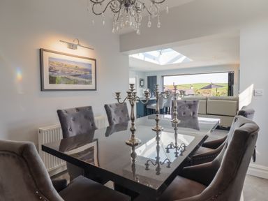 A dining room with a black table and gray chairs and silver candelabras at Bronallt in Cemaes Bay