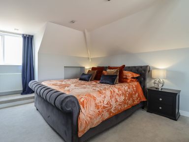 A bedroom with a bed with floral orange bedding and a bedside table with a lamp at Bronallt in Cemaes Bay