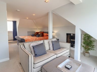 A seating area with a sofa and ottoman in front of a bed in a bedroom at Bronallt in Cemaes Bay