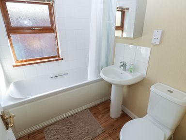 A bathroom with a bathtub, toilet, and sink at Riverside Lodge 3