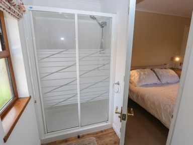 A shower and a bed visible from the bathroom at Riverside Lodge 3