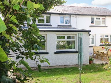 A garden with a house and furniture at Coach House Cottage in 