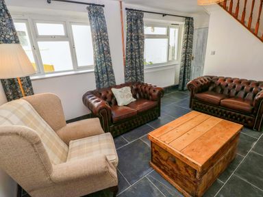 A living room with leather sofas and a wooden coffee table at Coach House Cottage 