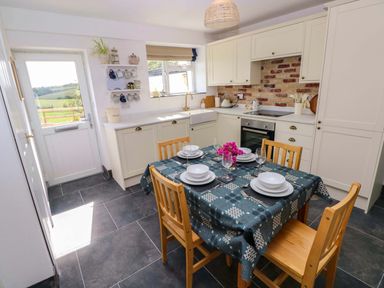 A kitchen with a dining table and chairs at Coach House Cottage