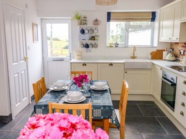 A kitchen with dining table and chairs at Coach House Cottage