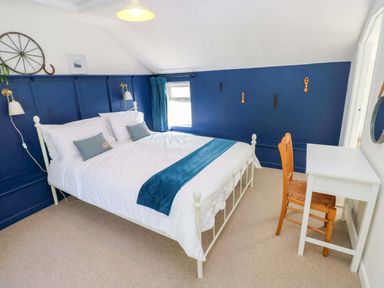 A bedroom with a bed and desk at Coach House Cottage