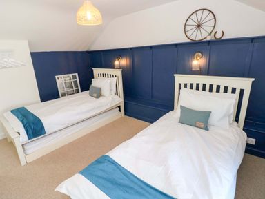 A bedroom with two beds and decorative items at Coach House Cottage