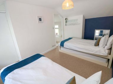 A bedroom with two beds and a light fixture at Coach House Cottage