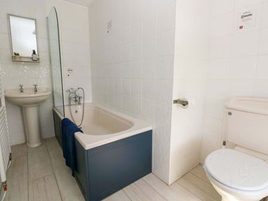 A bathroom with a bathtub, washbasin, and toilet at Coach House Cottage