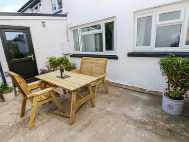 A wooden table and chairs with plants at Coach House Cottage 