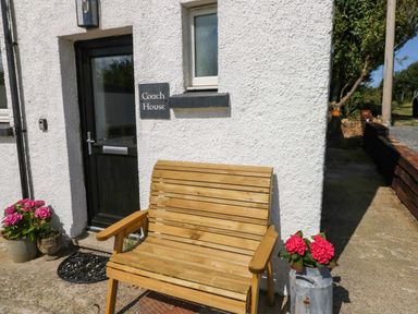 An outdoor area with a wooden bench and flower pot at Coach House Cottage