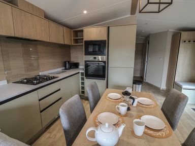A kitchen with a dining table set for tea at The Pines 2 Bedrooms Delamere