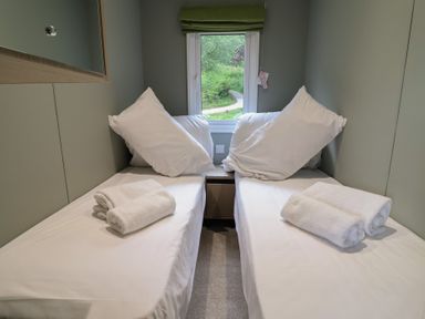 A bedroom with twin beds and towels at The Pines 2 Bedrooms in Delamere