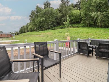 An outdoor area with chairs and decking at The Pines 2 Bedrooms Delamere